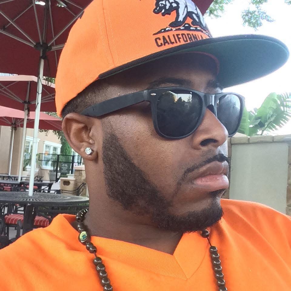 Ken Diesel wearing an orange California cap and sunglasses
